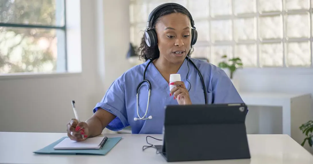 Doctor talking notes while talking to a tablet Doctor talking notes while talking to a tablet