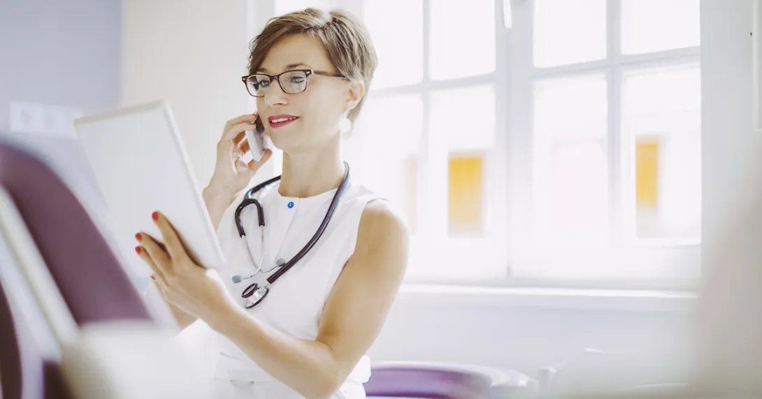 Doctor looking at tablet while on the phone