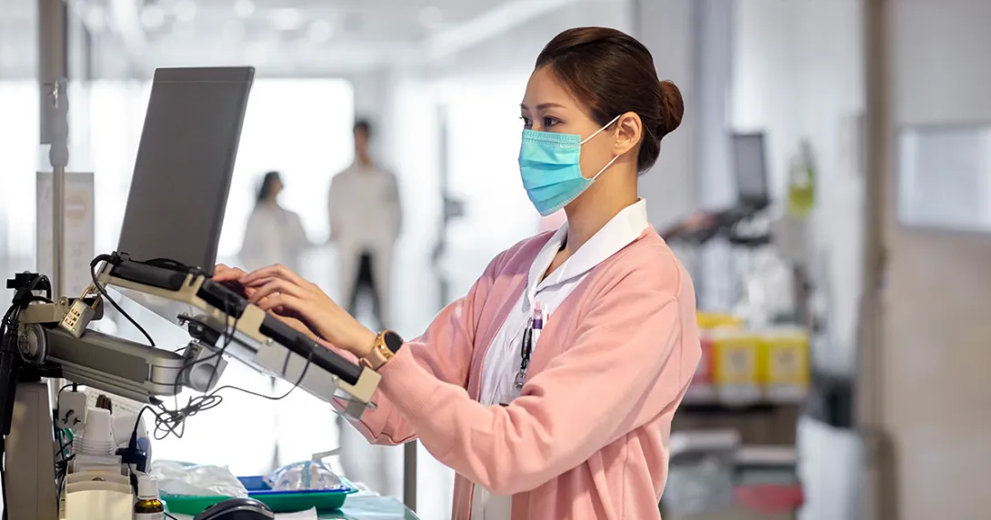 Healthcare worker in mask using laptop terminal