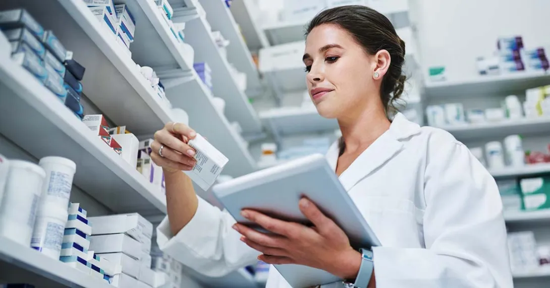 Pharmacist with a tablet looking at a medication box Pharmacist with a tablet looking at a medication box