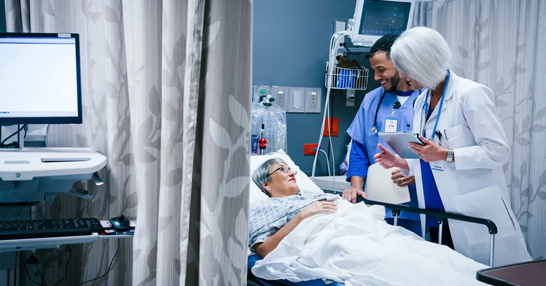 Healthcare workers talking to patient in hospital bed