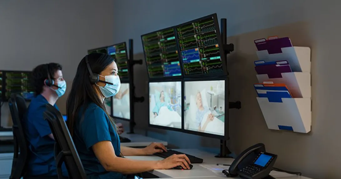 Healthcare workers in masks viewing patients on monitors
