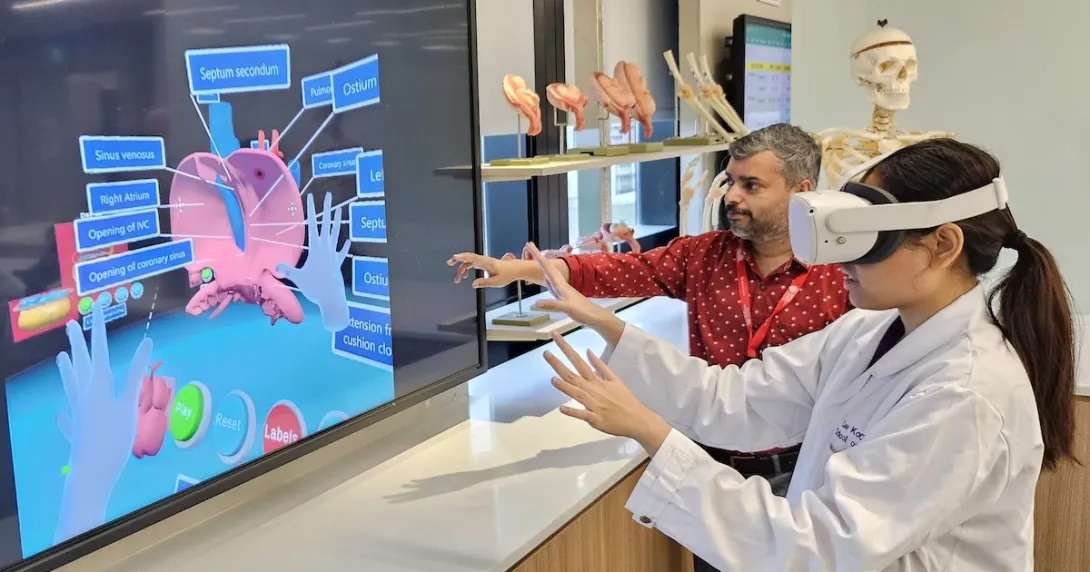 A medical student wearing a VR headset is learning the parts of the heart while being assisted by an instructor A medical student wearing a VR headset is learning the parts of the heart while being assisted by an instructor