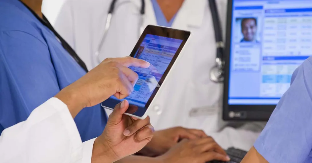 Healthcare workers looking at a medical record on a tablet Healthcare workers looking at a medical record on a tablet