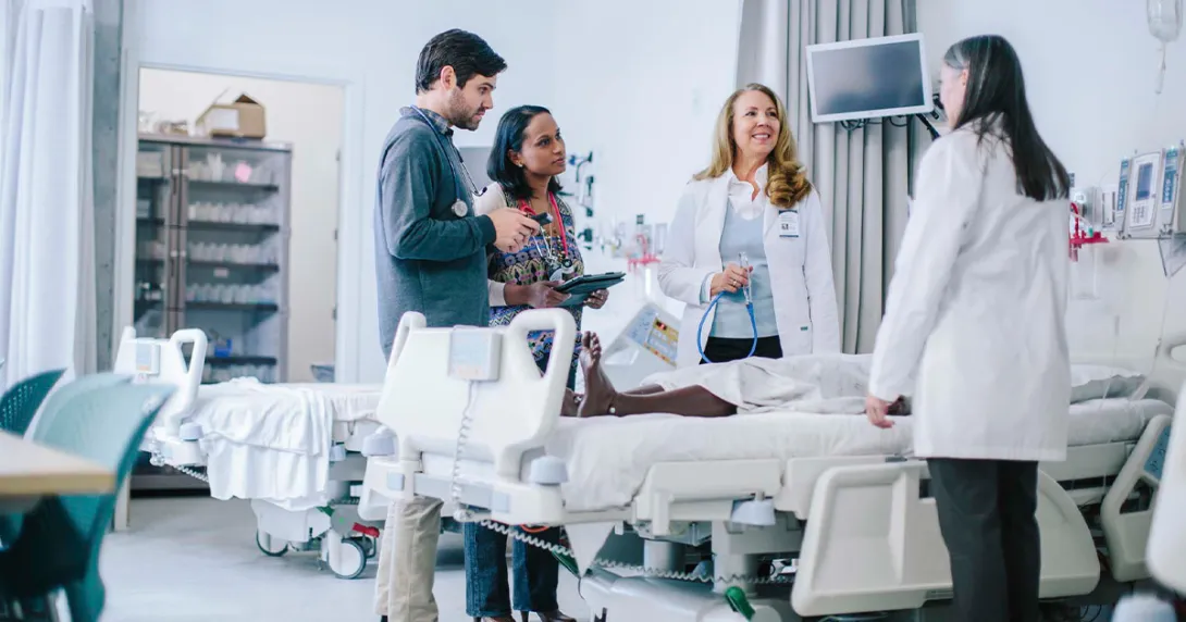 group of healthcare workers talking over hospital bed group of healthcare workers talking over hospital bed