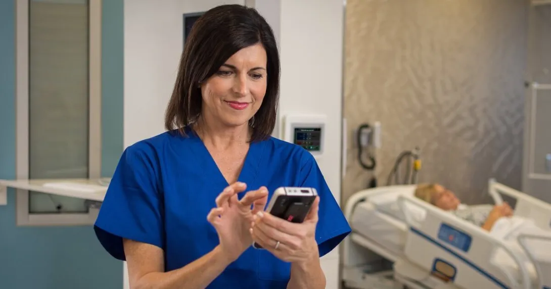 A nurse using a device under Ascom Intelligence