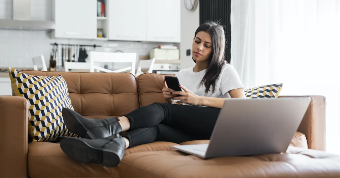 Woman on a couch at home checks her phone to book a doctor's appointment. Woman on a couch at home checks her phone to book a doctor's appointment.