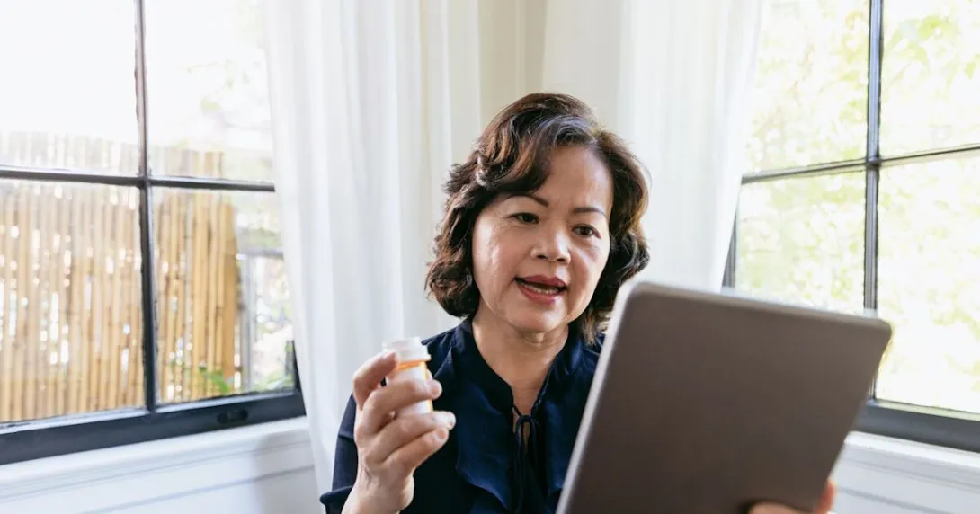 Woman with pill bottle talking into tablet