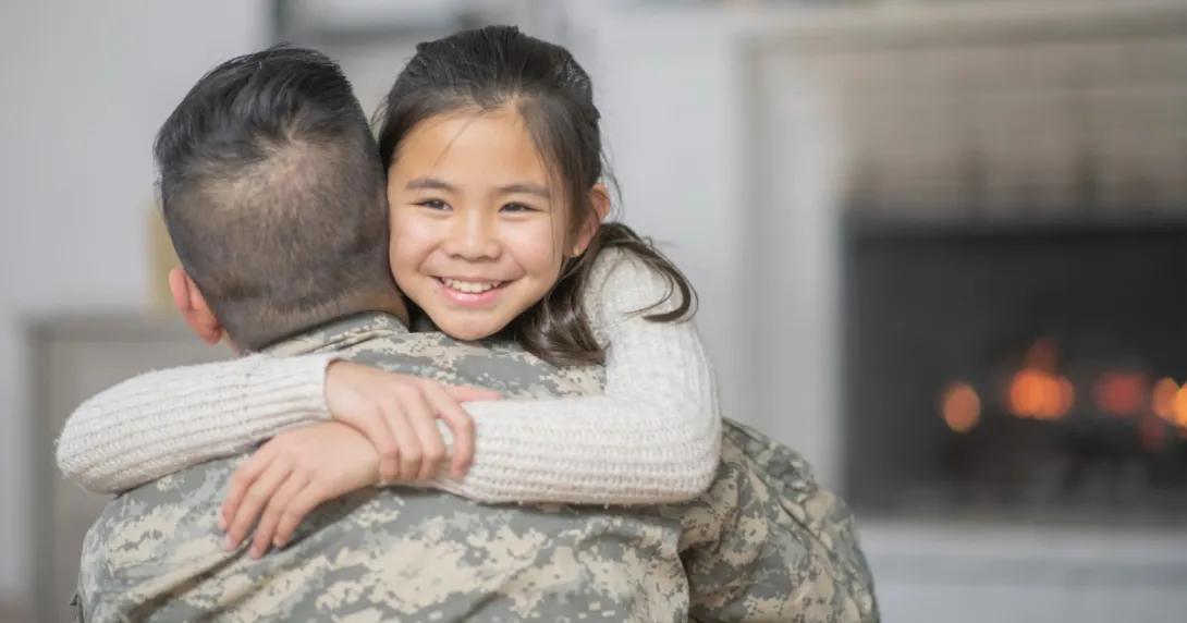 A parent in a military uniform hugging their child