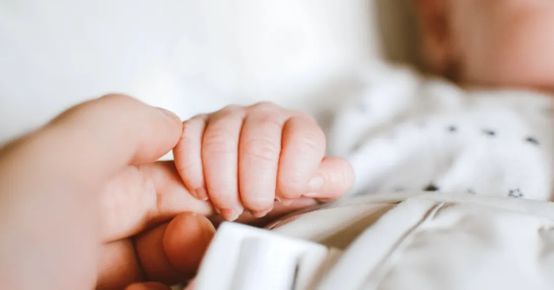 A baby grabbing an adult's finger