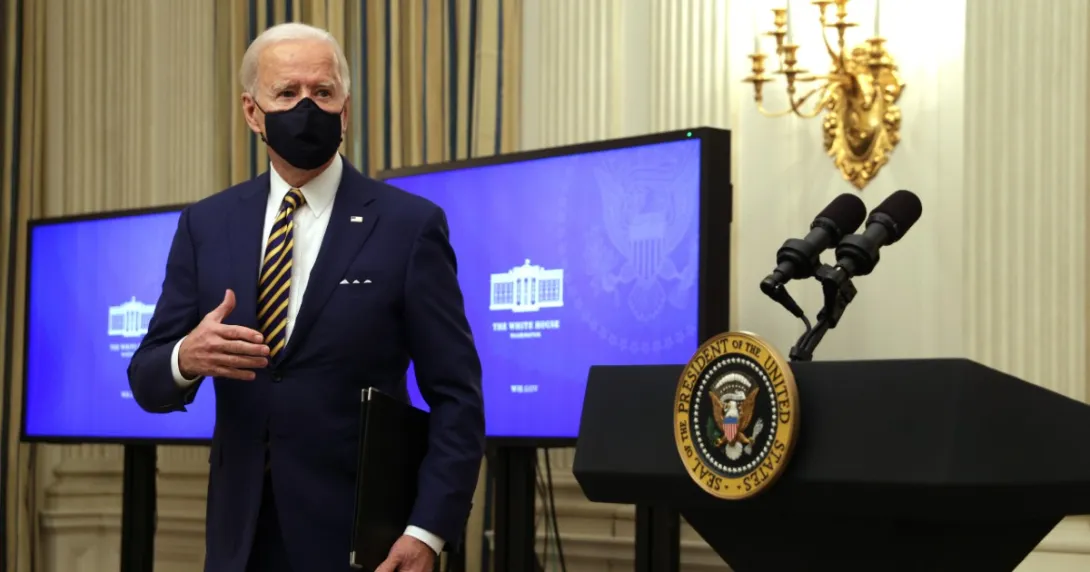 President Joe Biden stands in front of monitors