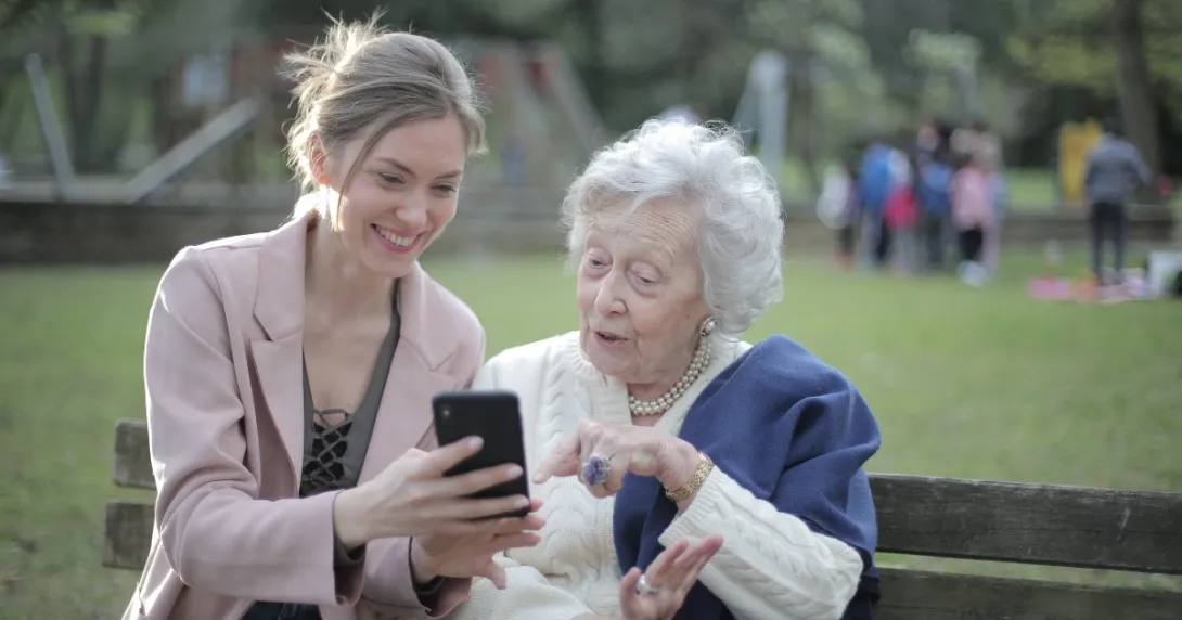 A younger person shows an older person something on the phone