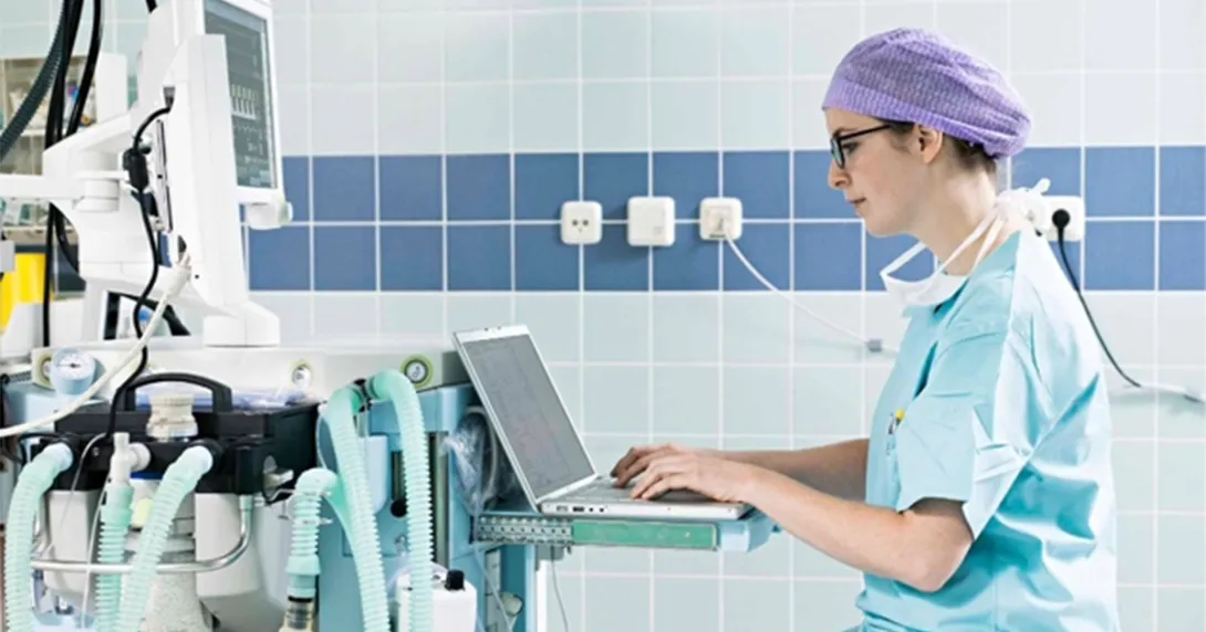 Clinician in scrubs at a hospital computer Clinician in scrubs at a hospital computer