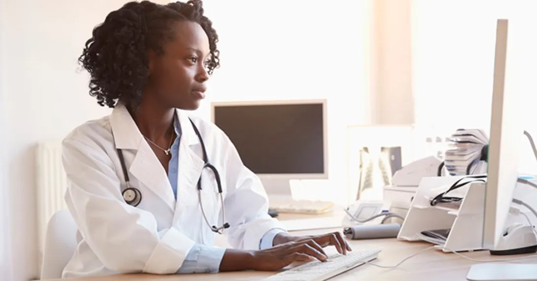 Person wearing stethoscope at a computer