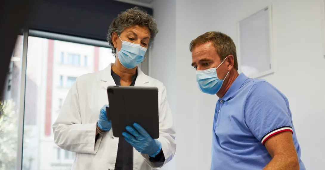 Doctor and patient look at information on a tablet Doctor and patient look at information on a tablet