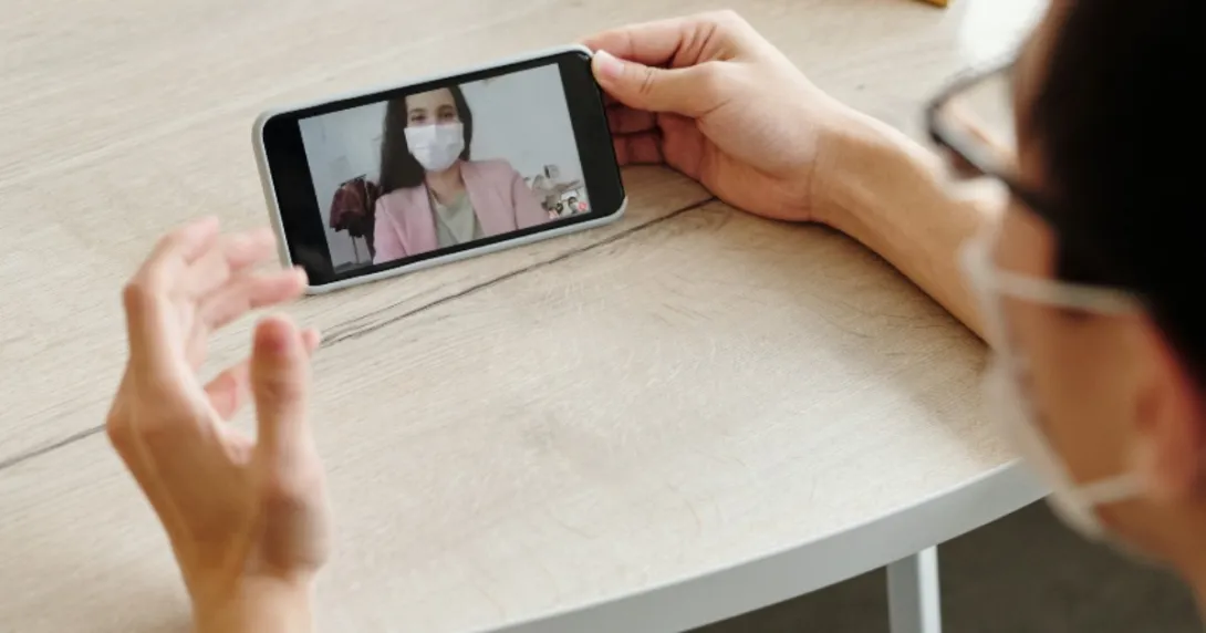 A person talking to a doctor in a mask on their phone
