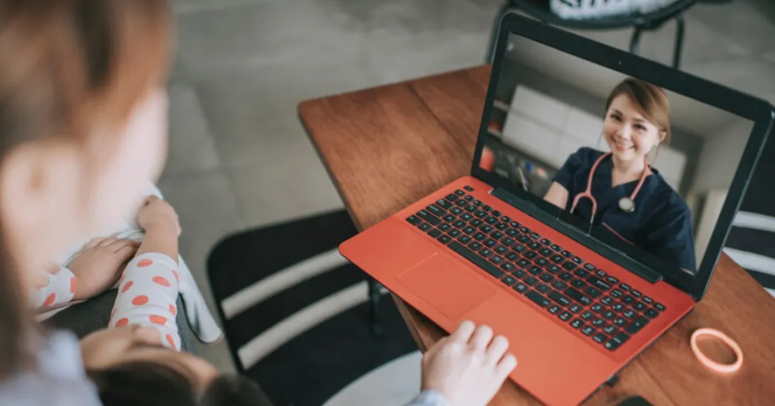 A person in scrubs appears on a laptop screen