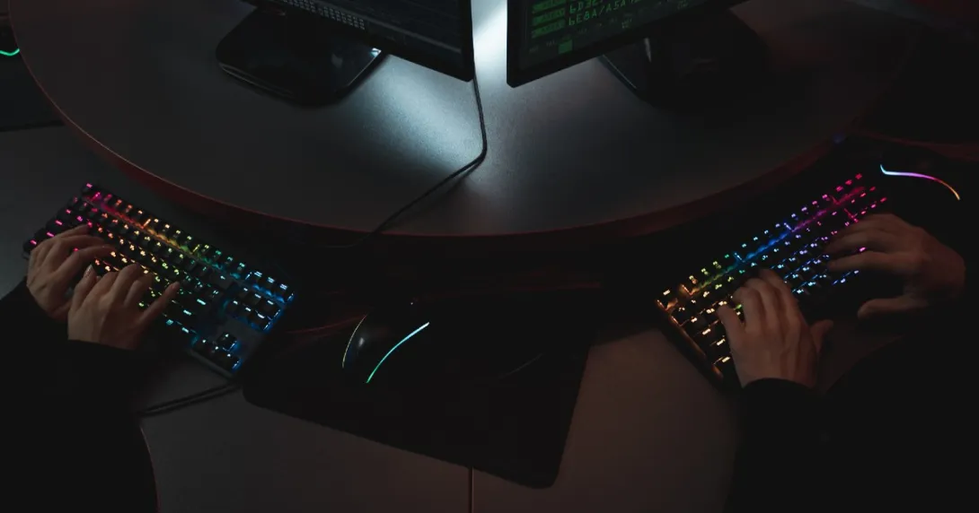 Two hackers side by side with hands on keyboards Two hackers side by side with hands on keyboards