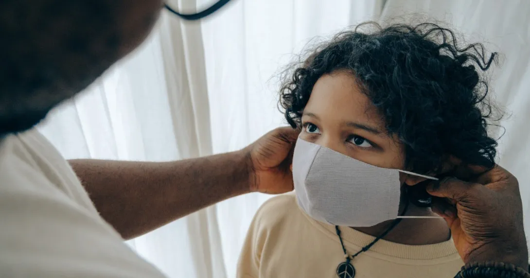 An adult puts a mask on a child