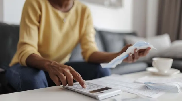 Person using calculator and holding piece of paper
