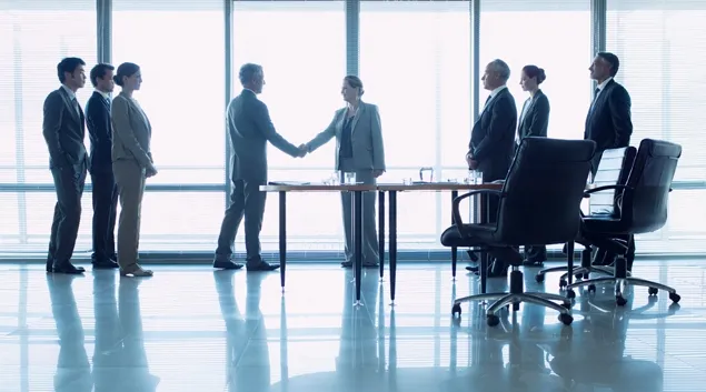 Group of businesspeople meeting with two shaking hands