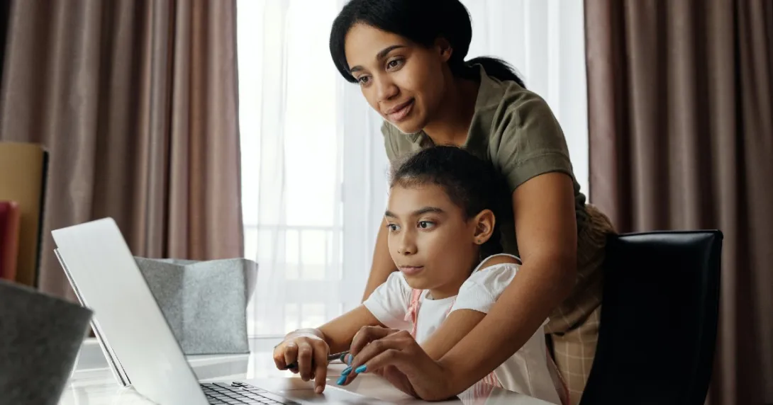 A parent and child look at a computer A parent and child look at a computer