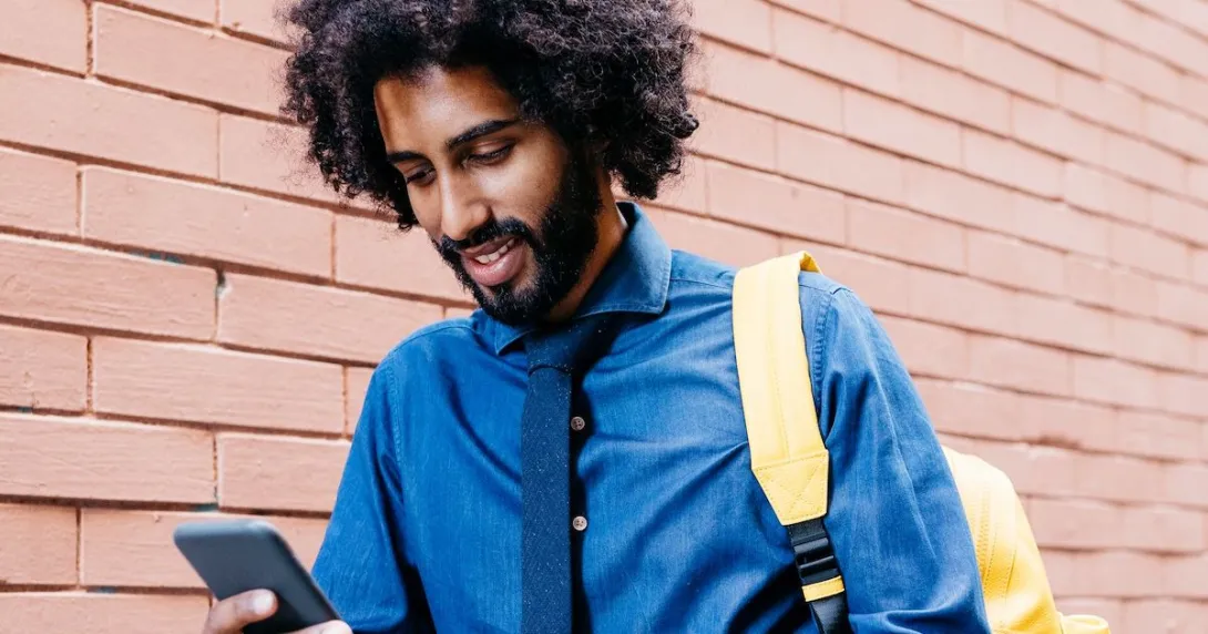 Man with backpack on mobile device Man with backpack on mobile device