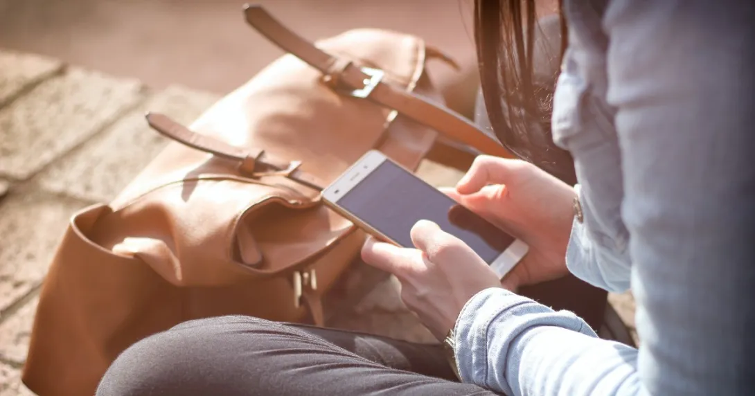 A person sitting on the floor holding their cellphone