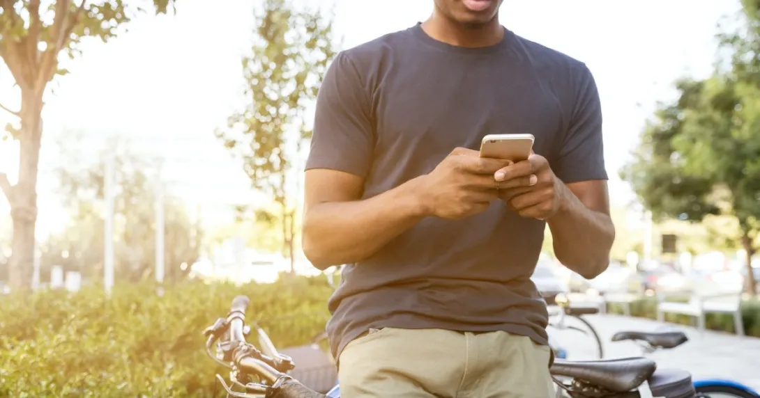 A person texting next to a bicycle