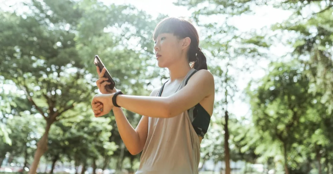 A person checking their smartwatch-tracked fitness data on their smartphone. A person checking their smartwatch-tracked fitness data on their smartphone.