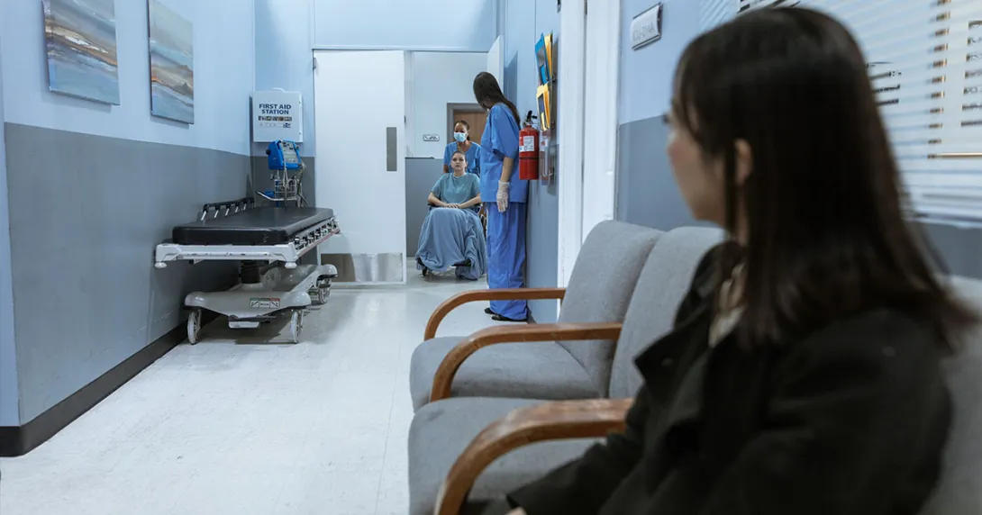Adult sits as child is wheeled out of a medical test. Adult sits as child is wheeled out of a medical test.