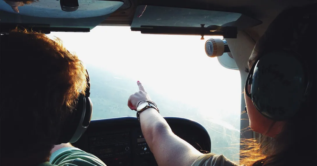 In a plane, a copilot points to a destination on the horizon. In a plane, a copilot points to a destination on the horizon.