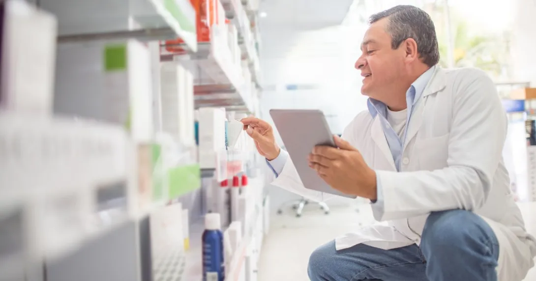 A pharmacist looks at a shelf of medications