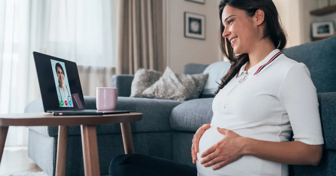 A pregnant person looking at a doctor onscreen