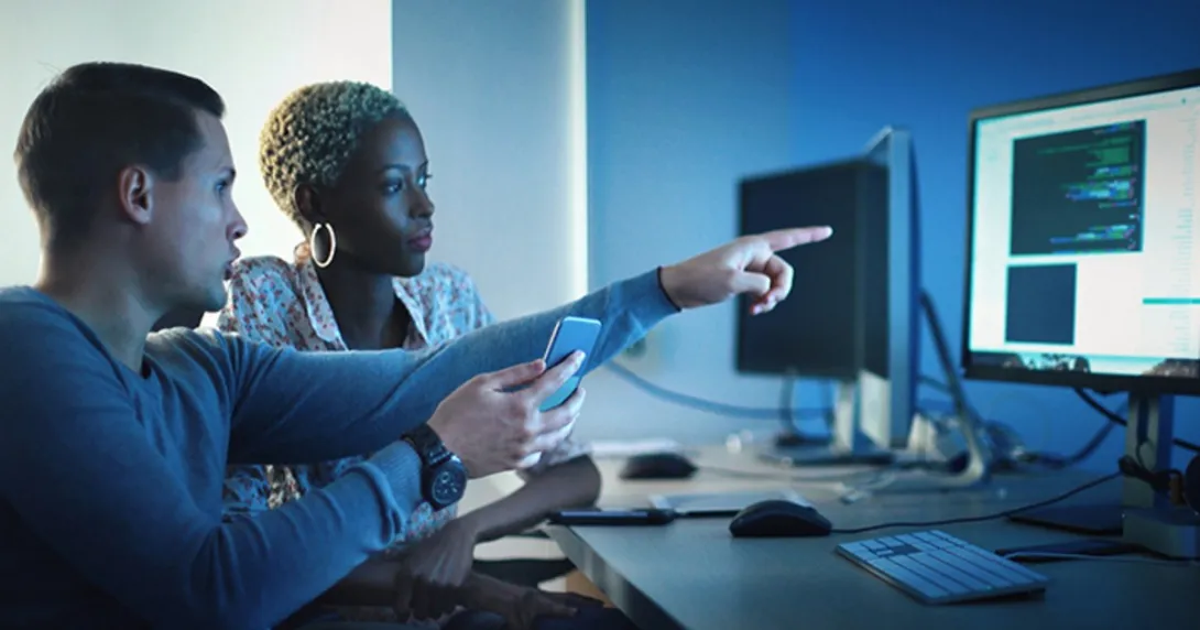 Two people at a desk examine a screen