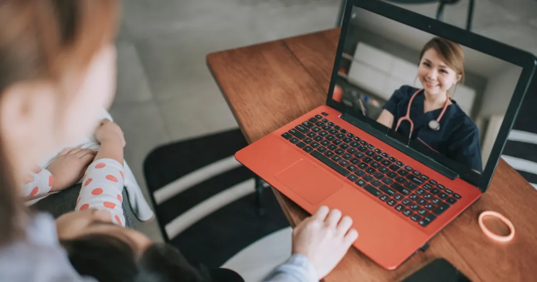 A patient with a baby on their lap speaks to a provider via telehealth
