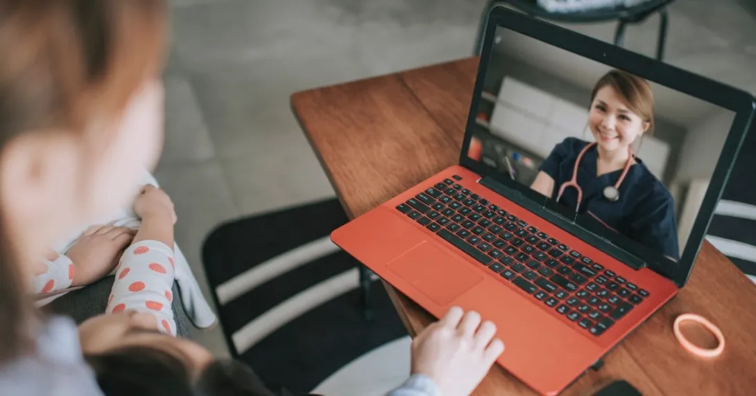 A doctor speaks to a parent and child via telemedicine