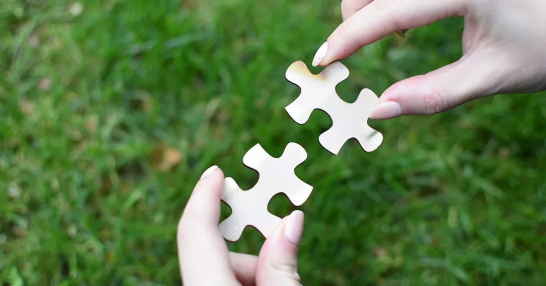 Hands fit two puzzle pieces together