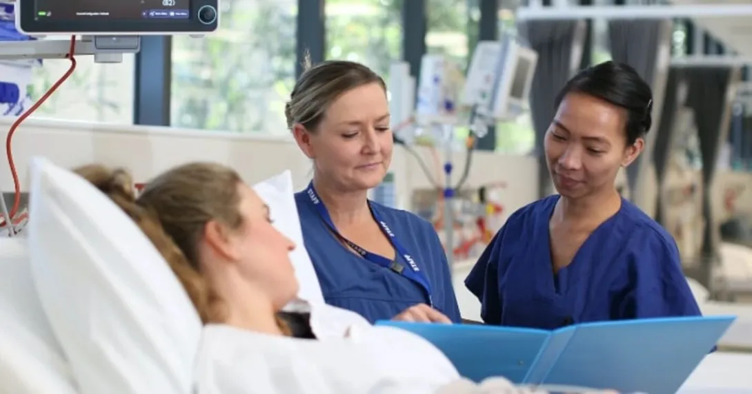 Nurses assisting a patient in bed