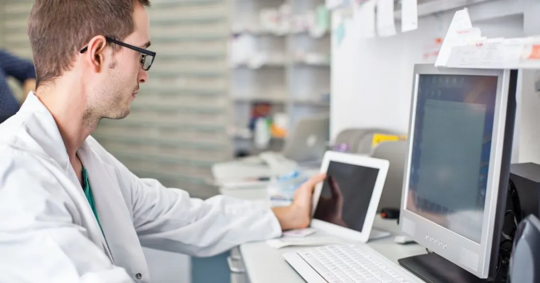 A clinician using both desktop computer and tablet