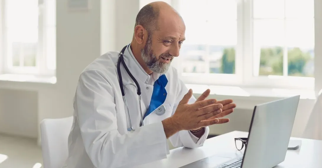 A doctor uses a laptop for an online consultation
