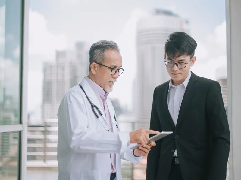 A doctor speaking with a person in a suit.