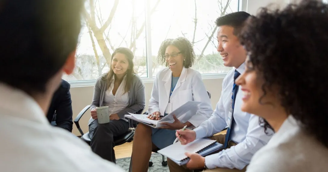 Smiling health system colleagues sit together and talk through AI concerns Smiling health system colleagues sit together and talk
