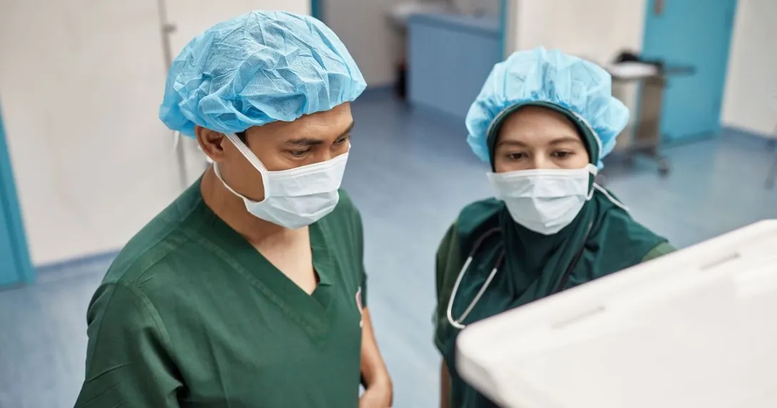 Two surgeons checking on an operation's progress through a digital monitor Two surgeons checking on an operation's progress through a digital monitor