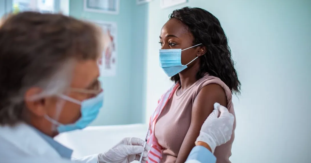 A woman wearing face mask getting vaccinated