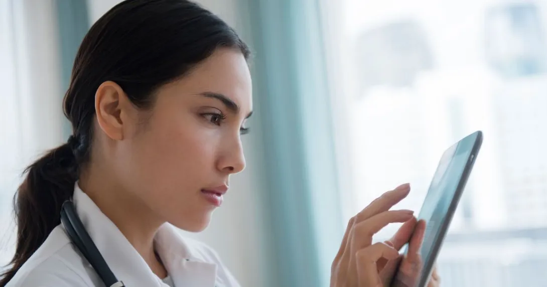 A doctor using a digital tablet to review a patient's file A doctor using a digital tablet to review a patient's file