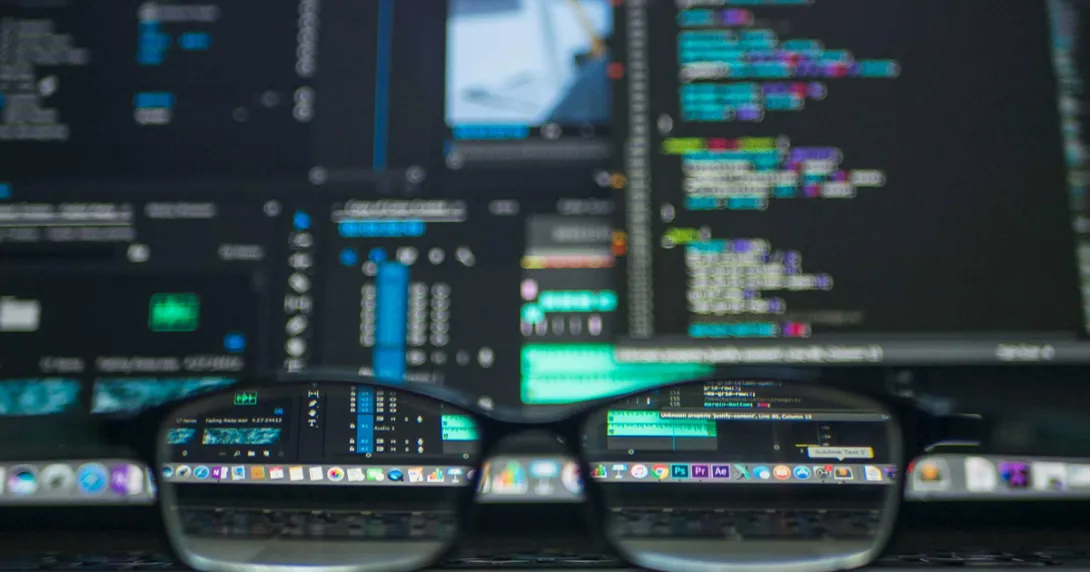 Glasses in front of computer screens with software code 