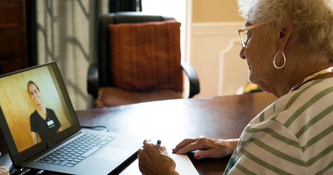 An elderly patient in a virtual consult with a doctor using a laptop computer