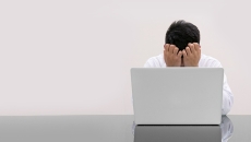 A doctor with their head in their hands in front of a computer