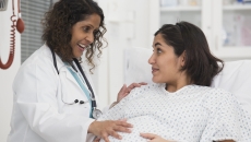 Doctor with hand on belly of pregnant patient